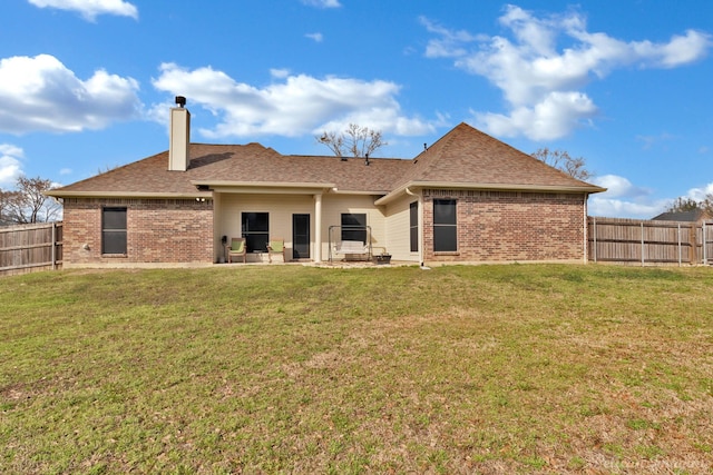 rear view of house featuring a yard, brick siding, and a fenced backyard