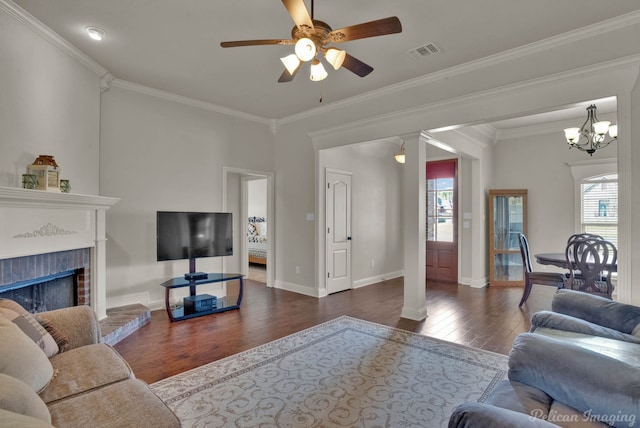 living area featuring a brick fireplace, crown molding, visible vents, and wood finished floors