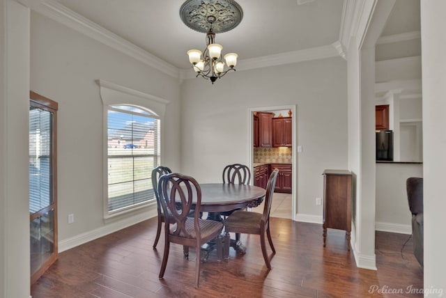 dining area with dark wood-type flooring, ornamental molding, baseboards, and an inviting chandelier