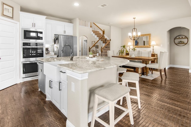 kitchen with a breakfast bar, visible vents, arched walkways, and stainless steel appliances