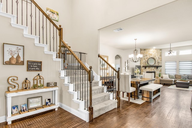 stairway with arched walkways, visible vents, wood finished floors, a chandelier, and baseboards