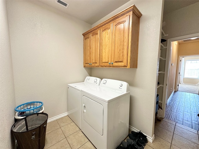 clothes washing area featuring cabinet space, baseboards, visible vents, and washing machine and clothes dryer