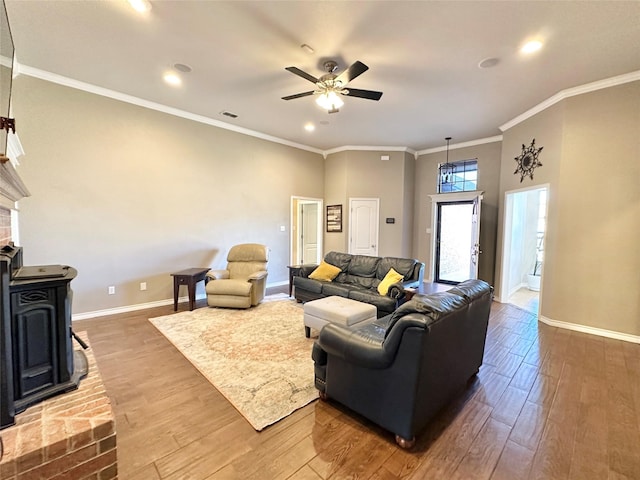 living area featuring ceiling fan, crown molding, baseboards, and wood finished floors