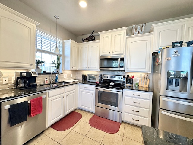 kitchen with appliances with stainless steel finishes, white cabinetry, a sink, and decorative backsplash