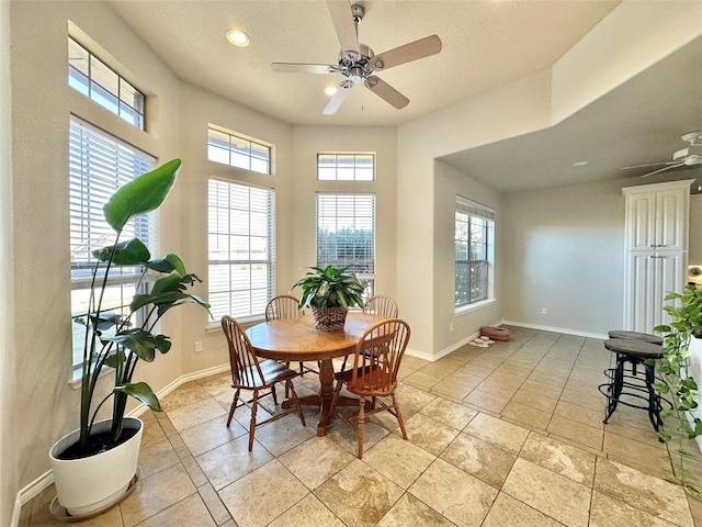 dining area featuring a ceiling fan, a wealth of natural light, and baseboards