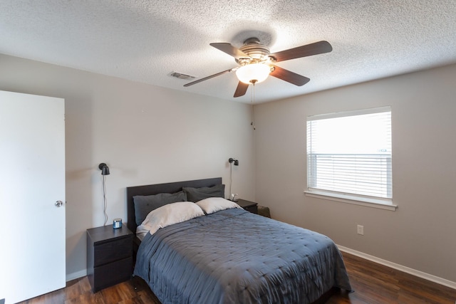 bedroom with a textured ceiling, dark wood-type flooring, visible vents, and baseboards