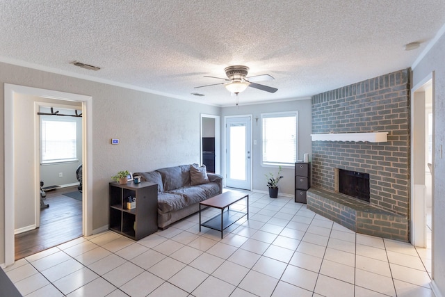 living area featuring light tile patterned flooring, a fireplace, visible vents, and ornamental molding