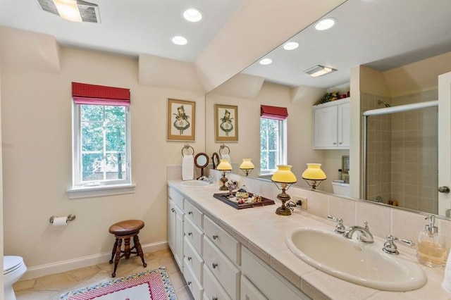 bathroom featuring toilet, a stall shower, a sink, and a wealth of natural light