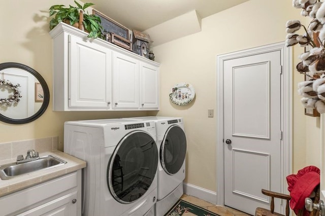 laundry area with washer and clothes dryer, cabinet space, light tile patterned flooring, a sink, and baseboards