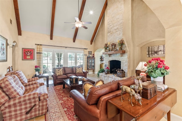 living room with visible vents, a ceiling fan, a stone fireplace, high vaulted ceiling, and beamed ceiling