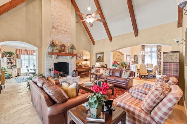 living room featuring arched walkways, beamed ceiling, a fireplace, high vaulted ceiling, and ceiling fan with notable chandelier