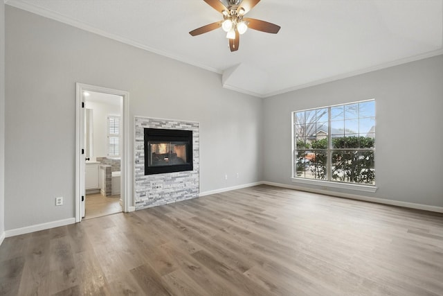 unfurnished living room with crown molding, a stone fireplace, wood finished floors, and baseboards