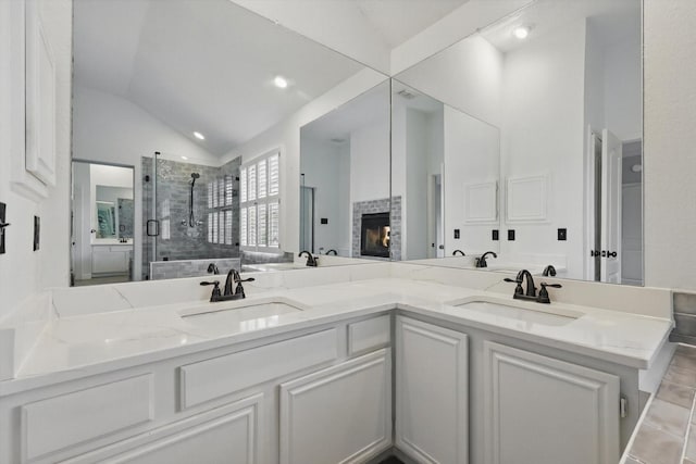 full bathroom featuring lofted ceiling, a stall shower, double vanity, and a sink