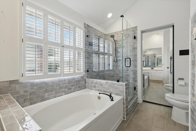 full bathroom with a garden tub, toilet, vanity, vaulted ceiling, and a shower stall