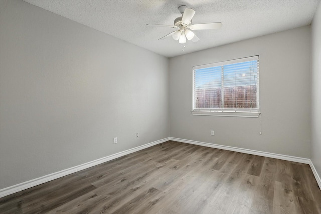 unfurnished room with a textured ceiling, wood finished floors, a ceiling fan, and baseboards