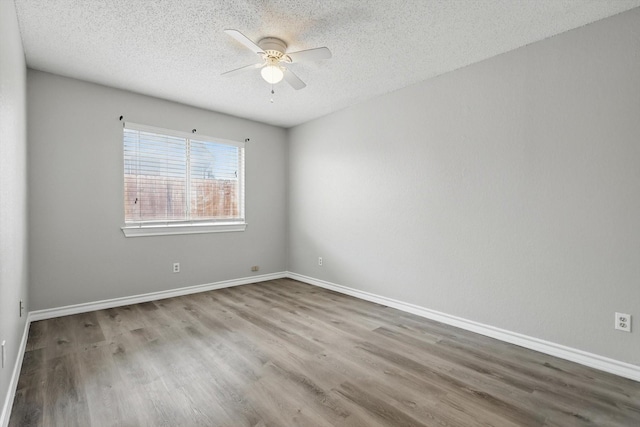 empty room featuring a ceiling fan, a textured ceiling, baseboards, and wood finished floors