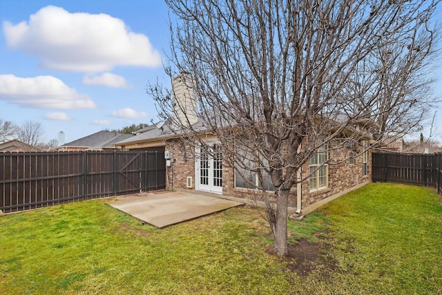 rear view of house with a patio, a fenced backyard, brick siding, french doors, and a lawn