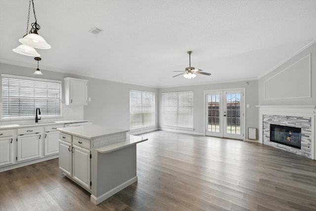 kitchen featuring light countertops, visible vents, ornamental molding, open floor plan, and a sink