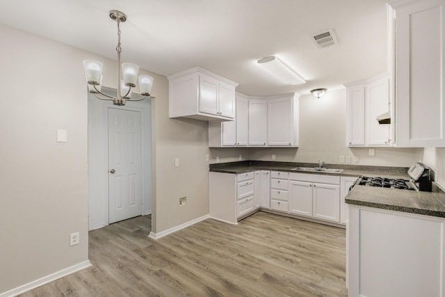 kitchen with visible vents, gas range oven, light wood-type flooring, white cabinetry, and a sink