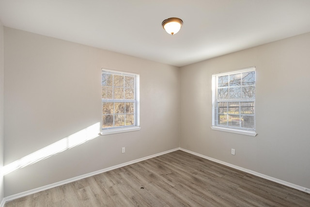 spare room with a healthy amount of sunlight, baseboards, and wood finished floors