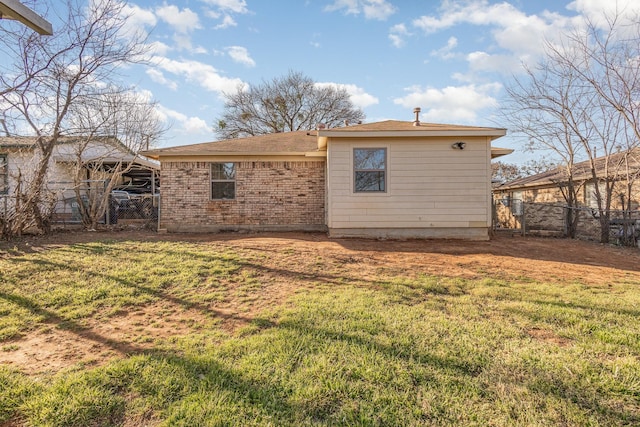 back of property featuring brick siding, a yard, and fence