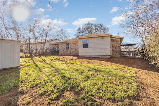 back of property featuring brick siding, a lawn, and fence