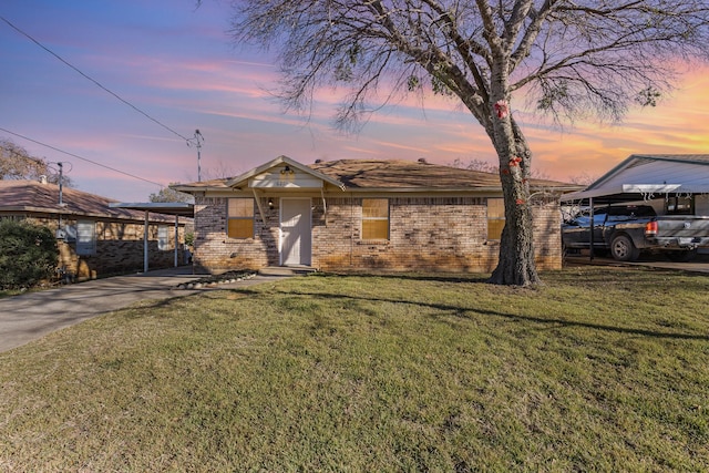 ranch-style home featuring driveway, brick siding, and a yard