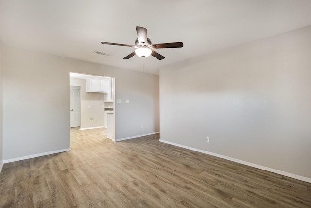 unfurnished room with light wood finished floors, baseboards, visible vents, and ceiling fan