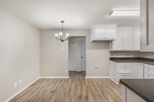 kitchen featuring dark countertops, light wood-type flooring, baseboards, and white cabinetry