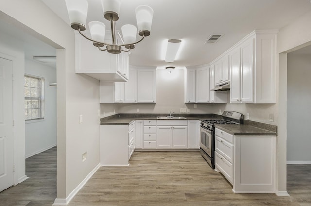 kitchen featuring visible vents, white cabinets, dark countertops, stainless steel gas range, and under cabinet range hood