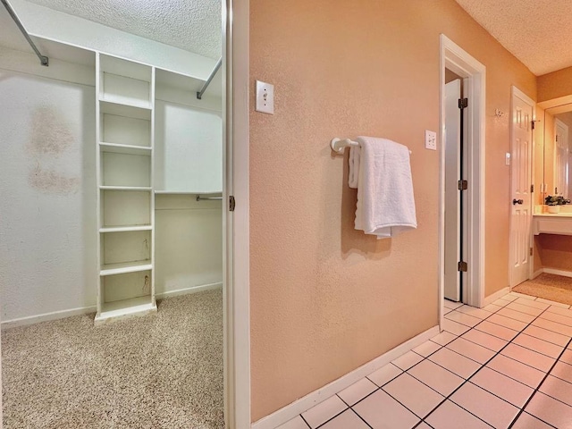 bathroom featuring a textured ceiling, a textured wall, and baseboards