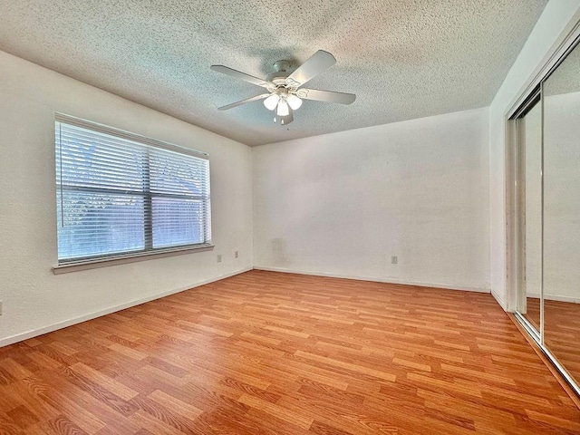 unfurnished bedroom with a textured ceiling, ceiling fan, a closet, and light wood-type flooring