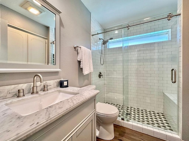 bathroom with toilet, a stall shower, wood finished floors, and vanity