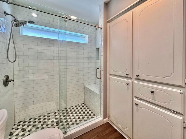 full bathroom featuring a stall shower, toilet, and wood finished floors