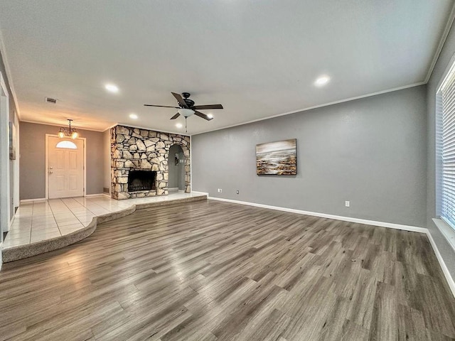 unfurnished living room with ornamental molding, a ceiling fan, visible vents, and wood finished floors