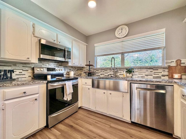 kitchen featuring decorative backsplash, appliances with stainless steel finishes, light wood-style floors, white cabinetry, and a sink