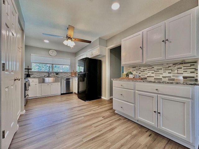 kitchen with appliances with stainless steel finishes, white cabinetry, a sink, and backsplash