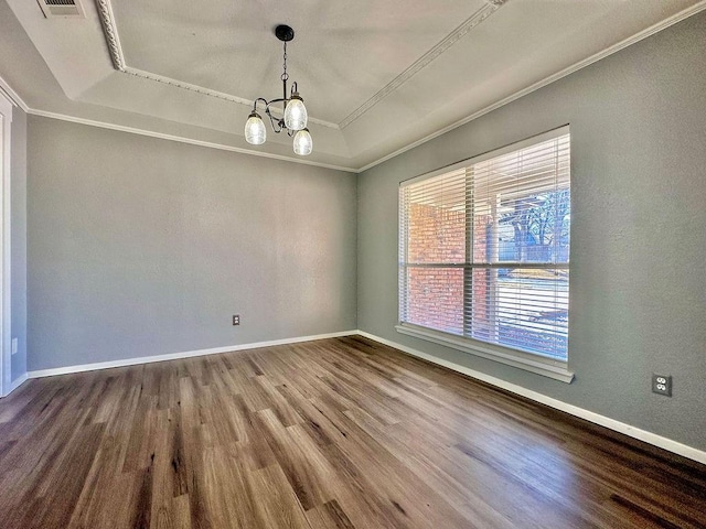 empty room featuring a notable chandelier, wood finished floors, baseboards, a raised ceiling, and crown molding