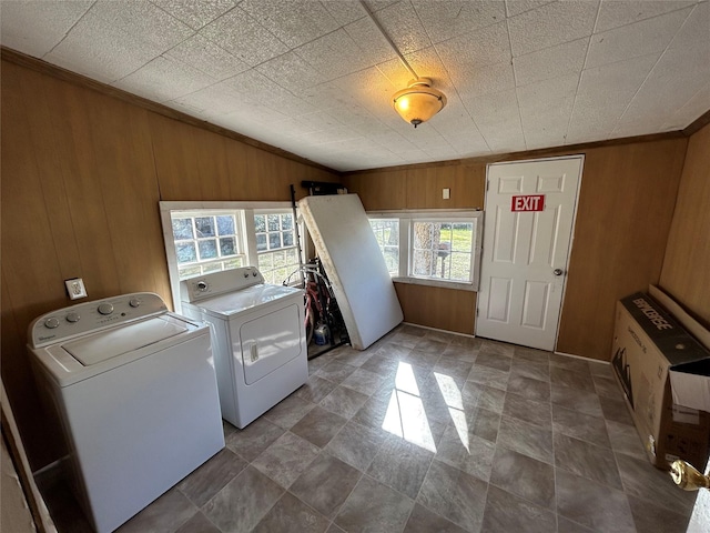 clothes washing area featuring washing machine and dryer, laundry area, and wood walls