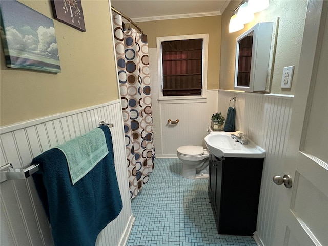 bathroom with a wainscoted wall, toilet, vanity, and crown molding