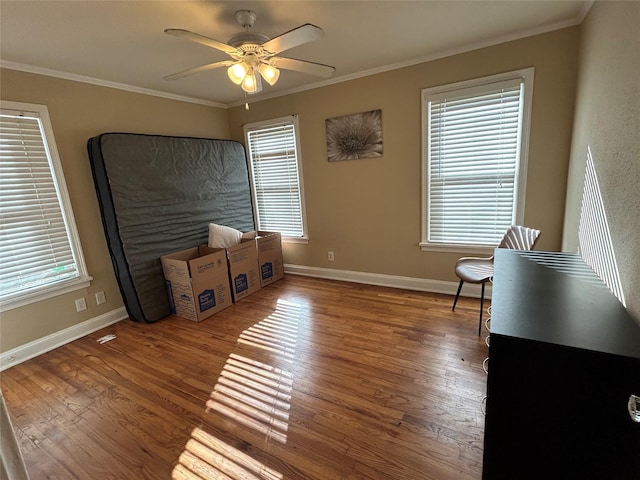 misc room with a ceiling fan, baseboards, ornamental molding, and wood finished floors