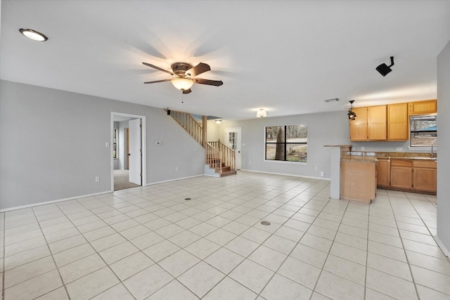 unfurnished living room featuring ceiling fan, stairway, baseboards, and light tile patterned floors