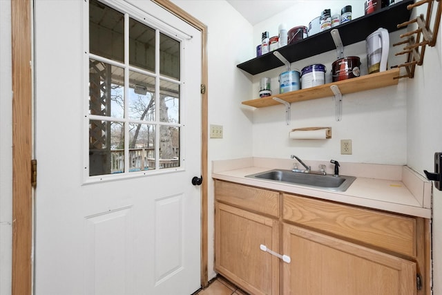 kitchen featuring light countertops, light brown cabinetry, open shelves, and a sink