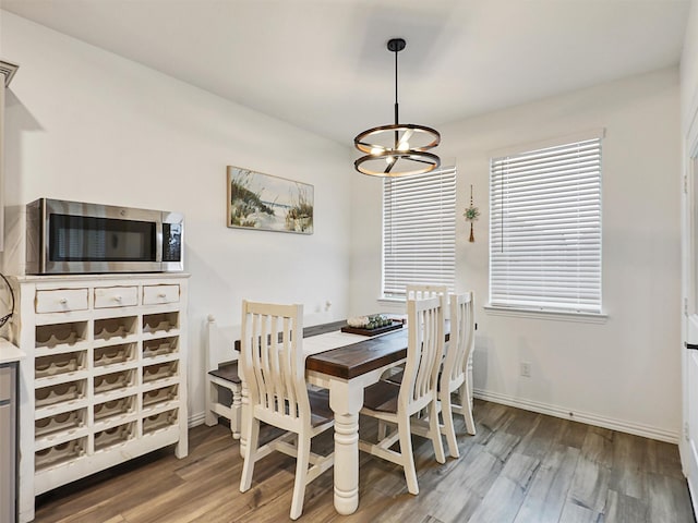 dining area featuring an inviting chandelier, baseboards, and wood finished floors