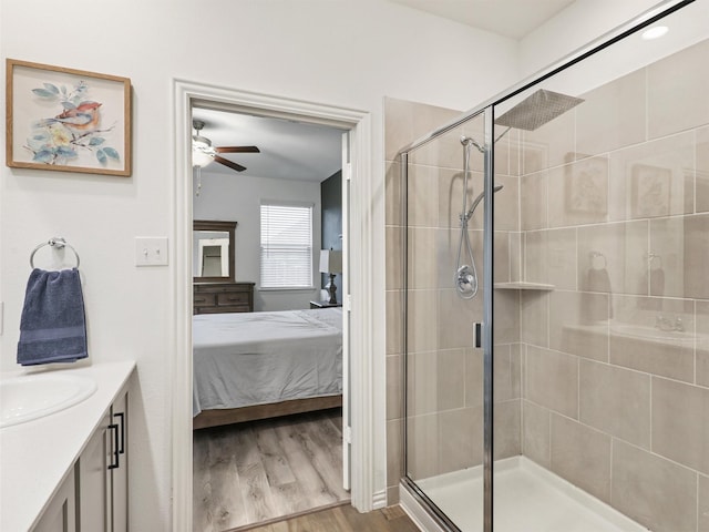 bathroom with ceiling fan, connected bathroom, a shower stall, and wood finished floors