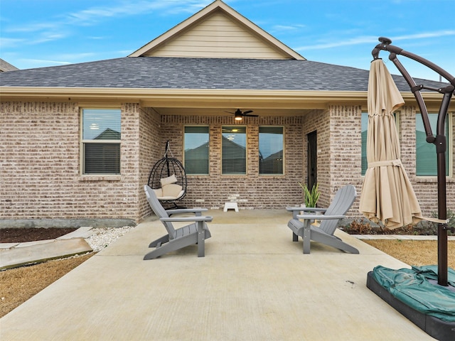 back of property with a shingled roof, brick siding, and a ceiling fan