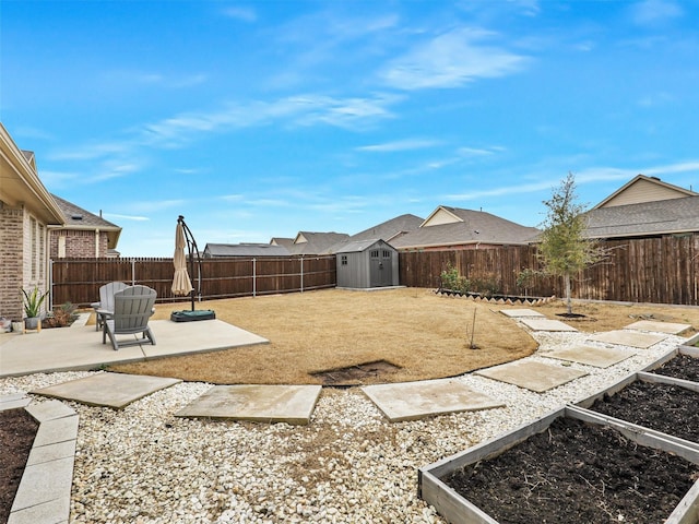 view of yard with a vegetable garden, a fenced backyard, a storage unit, an outdoor structure, and a patio area