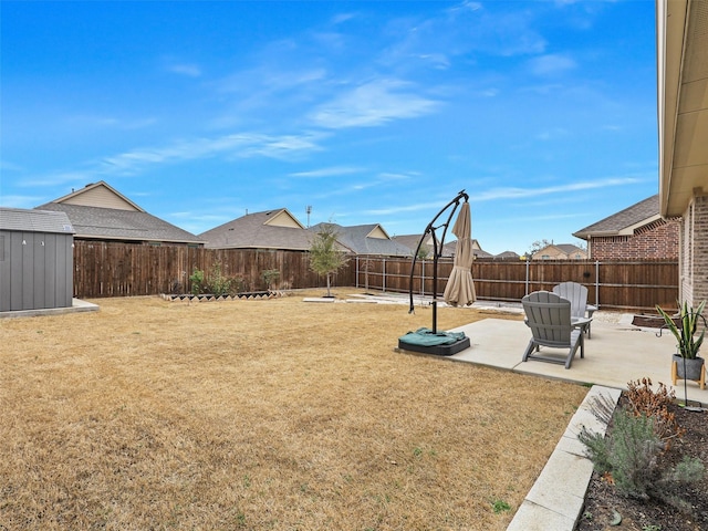 view of yard with an outbuilding, a fenced backyard, a patio, and a storage unit