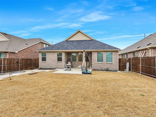 back of house featuring a patio, brick siding, roof with shingles, and a fenced backyard