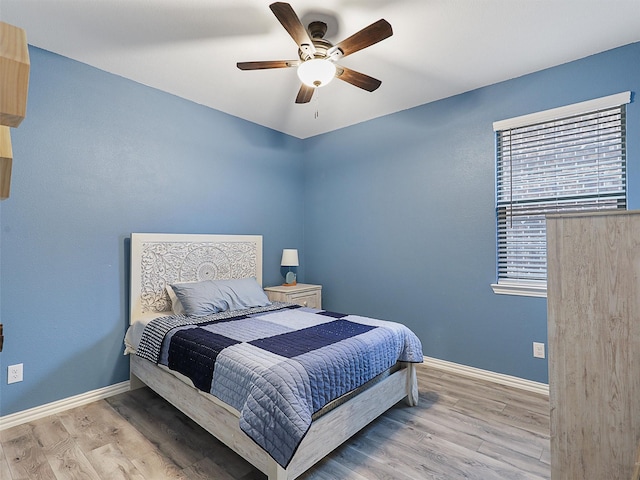 bedroom with a ceiling fan, baseboards, and wood finished floors